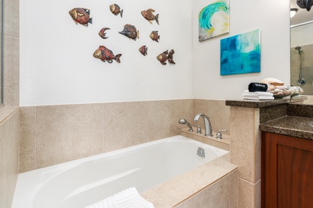 Ensuite primary bathroom with double vanity, walk-in shoer, and soaking tub