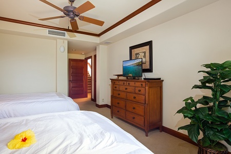 - Cozy bedroom with two queen beds facing a dresser and mounted flat screen TV   - Neutral tones and wood trim offer a warm, inviting feel for restful nights   - Ceiling fan and natural light ensure year round comfort for every guest