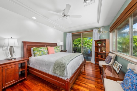 - Bright bedroom with king bed, hardwood floors, and tropical accents - Sliding glass doors open to a private balcony with garden views - Ceiling fan and open shelving add comfort and functionality