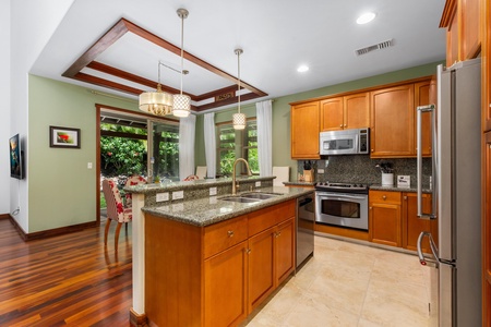 - Modern kitchen with granite countertops, wood cabinetry, and pendant lighting - Center island with sink overlooks the dining area and beautiful garden views - Stainless steel appliances offer both style and functionality