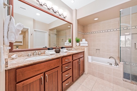 Ensuite primary bathroom with double vanity, walk-in shower, and soaking tub