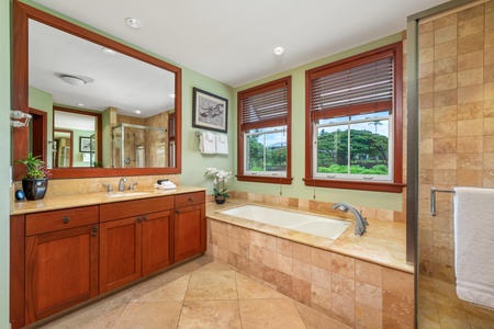 Step into your spa-inspired bathroom with warm tile throughout, a large soaking tub, and windows overlooking lush greenery. Rich wood accents and spacious vanity create a peaceful retreat for your daily routine.