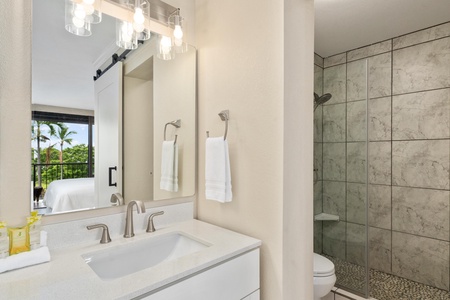 - White vanity with polished chrome fixtures opens to a tiled walk in shower - Modern lighting, soft towels, and spa touches create a peaceful morning routine - Sliding door design adds privacy while keeping the suite feeling open