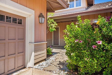 Front walkway entrance framed by shrubs and stone pathway.
