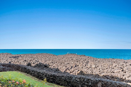 Stunning ocean views stretch endlessly across brilliant turquoise waters, framed by volcanic rock formations and tropical landscaping.