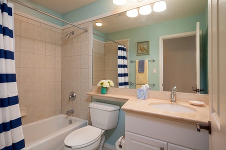 - Full bathroom with a tiled tub shower combo, spacious counter, and bright vanity lighting - Soft teal wall and beachy accents create a fun, fresh feel - Everything you need for a refreshing start or relaxing wind down is right here