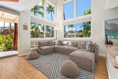 Sink into plush gray seating while soaking up tropical palm views through soaring windows in your bright, airy living space.
