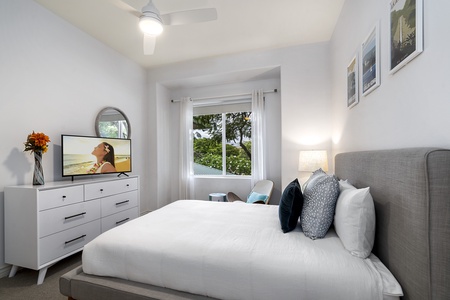 - Queen bedroom with crisp white bedding and stylish throw pillows   - Window view of greenery creates a serene and calming retreat   - Modern dresser and wall mounted TV offer both storage and entertainment