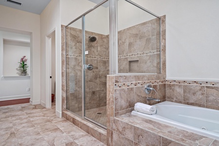 Ensuite primary bathroom with double vanity, walk-in shower, and soaking tub