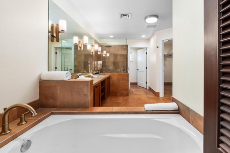 Unwind in your luxurious spa-like bathroom featuring rich wood vanities, soaking tub, and elegant pendant lighting.