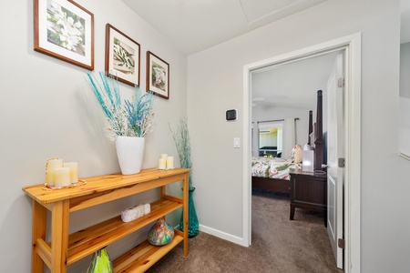 - Charming hallway with tropical prints and vibrant floral arrangements on display - Natural wood console table adds warmth and houses beachy decorative accents - Leads into the bedroom with colorful bedding and bright window views