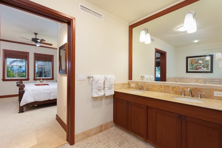 - Vanity area with a framed mirror & warm wood cabinetry for a cozy yet elegant touch - Neutral toned tile flooring & stone countertop create a clean & inviting bathroom ambiance - Convenient location next to the bedroom for quick access & guest comfort