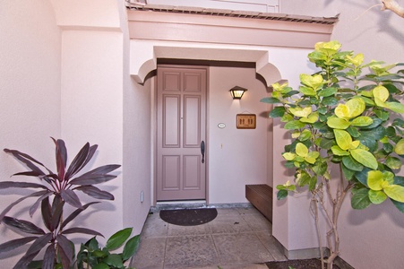 - Arrive at a welcoming front entry with soft pastel door and arch detail   - Outdoor lighting and tropical plants enhance the inviting feel   - Step inside to begin your relaxing coastal getaway