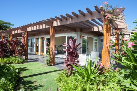 Modern fitness center building framed by a pergola and vibrant greenery.