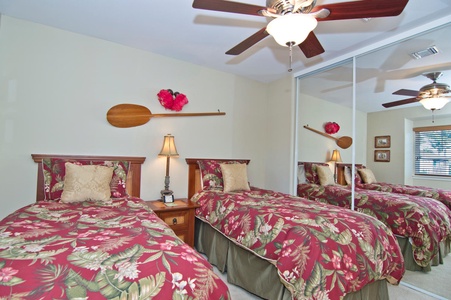 - Rest in a cheerful twin bedroom with tropical red bedding and plush pillows   - Mirrored closet doors reflect natural light and make the space feel open   - Nautical themed decor with a wall mounted paddle adds a playful touch