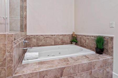 Ensuite primary bathroom with double vanity, walk-in shower, and soaking tub