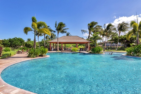Stunning resort-style pool surrounded by tropical palms and covered pavilion, perfect for relaxing days under Hawaiian sunshine.