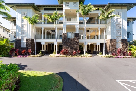 Elegant multi story condominium building with tropical landscaping and tall palm trees.