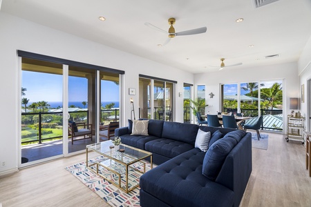 - Spacious living room with navy sectional and panoramic ocean views   - Floor to ceiling windows fill the space with natural light and breezes   - Open flow leads seamlessly to dining and outdoor lanai seating
