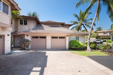 Spacious driveway and dual garage framed by tropical palms.