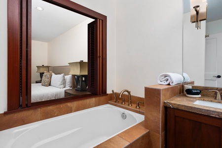 Unwind in your luxurious soaking tub with rich wood accents and plush towels, while enjoying views into your serene bedroom retreat.