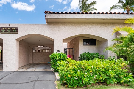 Arched carport and gated entrance surrounded by beautiful foliage.