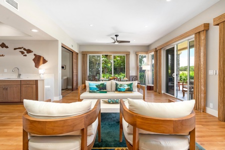 - Cozy lounge with stylish wood framed chairs & plush cushions offering relaxing comfort - Large windows & sliding doors open to greenery and an inviting patio space - Tropical themed pillows & warm lighting create a welcoming atmosphere for unwinding