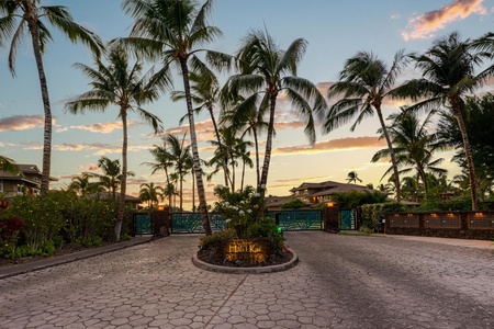 Tropical gated entry beautifully framed by palms and warm skies.