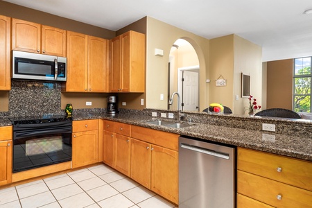 Your fully-equipped kitchen features granite countertops, modern appliances, and warm wood cabinetry—perfect for preparing home-cooked meals with natural light streaming in.