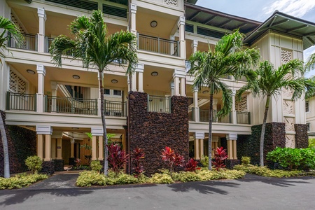 A tropical resort building with multiple balconies framed by lush palm trees and vibrant landscaping creates an inviting island atmosphere.