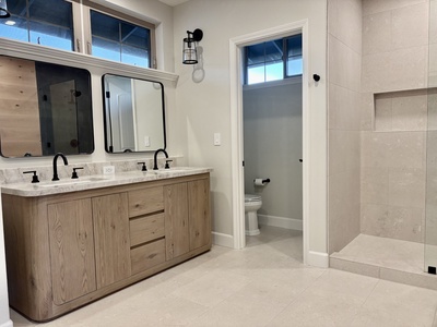 Enjoy a spa-inspired primary bathroom with limestone floors and shower, leathered quartzite countertops, and premium Rohl fixtures