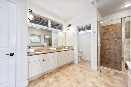 Ensuite primary bathroom with double vanity, walk-in shower, and soaking tub