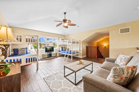 Loft with two twin bunk beds and a sofa  as well as wall mounted TV