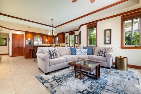 - Spacious living room with plush sectional sofa, patterned rug, and warm wood accents   - Open layout connects to modern kitchen and dining areas for easy entertaining   - Large windows invite in natural light, enhancing the welcoming feel