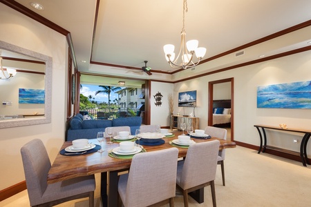 - Elegant dining area with rustic wood table set for six and modern chandelier   - Open layout flows into the living room and lanai for easy entertaining   - Tropical views create a relaxed yet sophisticated atmosphere