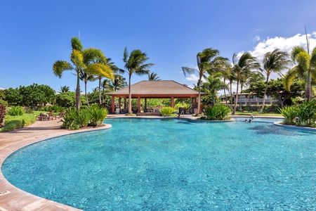 Resort style pool with pavilion seating and swaying palm trees.