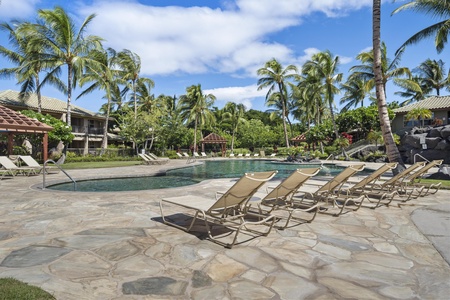 Resort-style pool area surrounded by swaying palm trees and tropical landscaping creates a serene island paradise atmosphere.