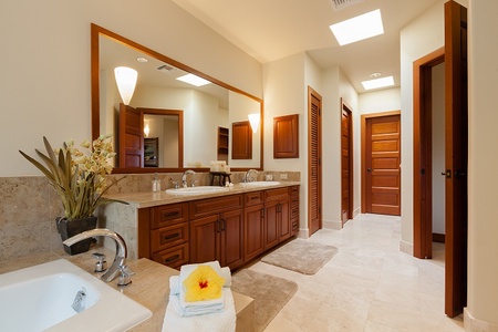 - Stylish bathroom with double vanity and large framed mirror   - Warm wood cabinetry contrasts beautifully with marble countertops   - Fresh towels and tropical flower detail create a spa inspired setting