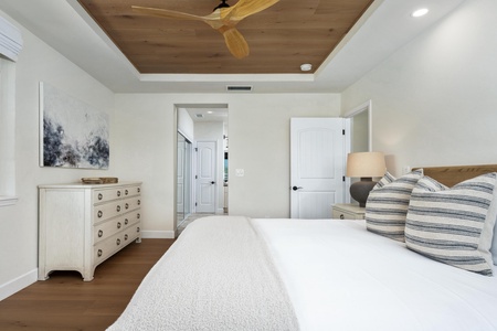 Unwind in your serene bedroom featuring crisp white linens, coastal decor, and warm wood ceiling details that create the perfect retreat.