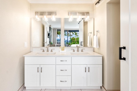 - Sleek dual vanity with white cabinetry, large mirror, and designer lighting - Bright tropical views reflect through the glass, adding depth and beauty - Ideal for couples or guests who want space and spa style function