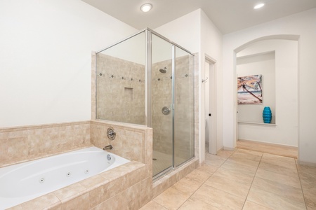 Unwind in your elegant bathroom featuring a jetted soaking tub and spacious glass shower with dual rainfall heads for ultimate relaxation.