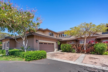 Driveway and two car garage surrounded by tropical plants.