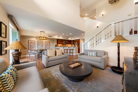 Unwind in your spacious living area with plush sofas, warm lighting, and an open layout flowing into the modern kitchen.