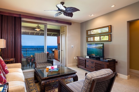 - Elegant living room with island style furniture and direct access to the lanai and sea breeze - Large TV and ceiling fan offer comfort and entertainment after a beach day - Wide glass doors showcase panoramic ocean views from inside
