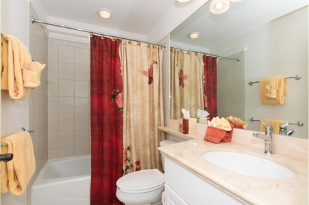 - Freshen up in a bright bathroom with a tub and shower combo   - Vibrant red and beige floral shower curtain adds a warm touch   - Spacious vanity with mirror and essentials for your daily routine