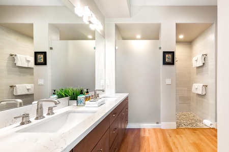 - Sleek bathroom design with double vanity white countertop and under mount sink - Frosted glass partition leads to spacious walk in shower for privacy and comfort - Decorative accents and recessed lighting add style and warmth to the space