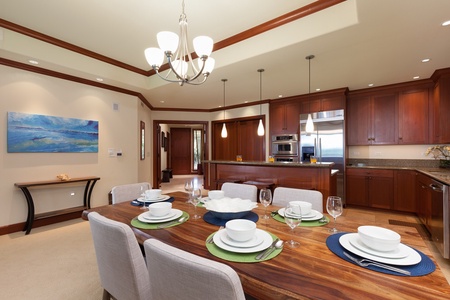 - Elegant dining area with rustic wood table set for six and soft upholstered chairs   - Chandelier lighting adds a warm glow over the space   - Open layout flows seamlessly into the gourmet kitchen for easy entertaining