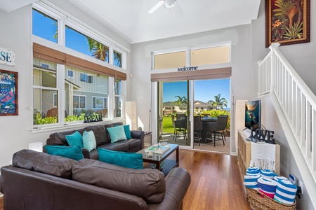 - Relax in a bright lounge with vaulted ceilings and sunlight streaming through tall windows - Brown leather sofas with teal pillows offer cozy comfort for movie nights - Step outside through sliding doors to enjoy the tropical breeze