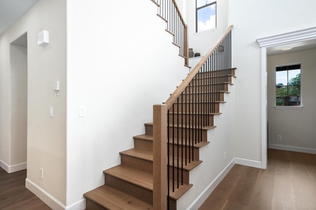 Your stylish staircase leads to private upper levels, featuring warm wood tones and sleek black railings in this bright, open entryway.