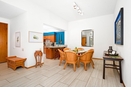 - Open dining area with tropical wicker chairs and a round glass table ready for shared meals - Track lighting and a large mirror reflect the bright, inviting space - Just steps from the kitchen, it's perfect for family breakfasts or dinner gatherings